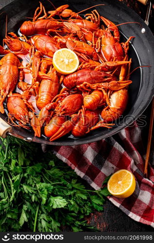 Boiled crayfish in a pot with parsley and lemon. Against a dark background. High quality photo. Boiled crayfish in a pot with parsley and lemon.