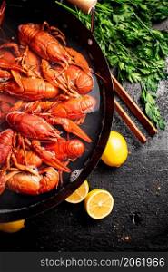 Boiled crayfish in a pot with parsley and lemon. On a black background. High quality photo. Boiled crayfish in a pot with parsley and lemon.