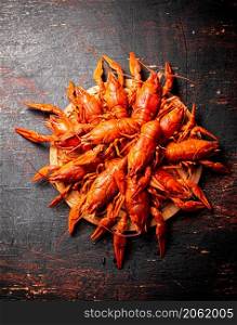 Boiled crayfish on a round cutting board. Against a dark background. High quality photo. Boiled crayfish on a round cutting board.