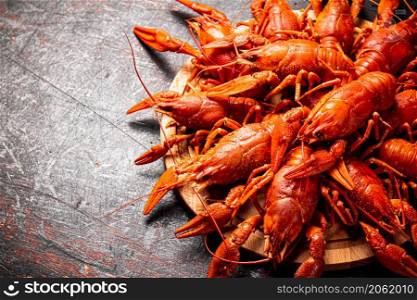 Boiled crayfish on a round cutting board. Against a dark background. High quality photo. Boiled crayfish on a round cutting board.