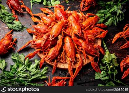 Boiled crayfish on a wooden cutting board with parsley. Against a dark background. High quality photo. Boiled crayfish on a wooden cutting board with parsley.