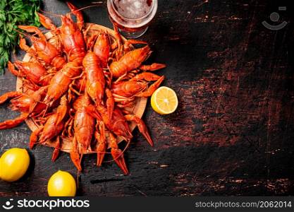 Boiled crayfish with a glass of beer and lemon. Against a dark background. High quality photo. Boiled crayfish with a glass of beer and lemon.
