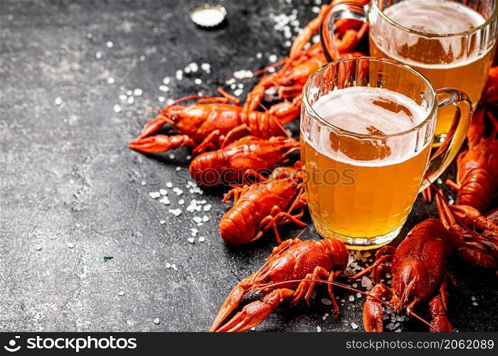 Boiled crayfish with a glass of beer. On a black background. High quality photo. Boiled crayfish with a glass of beer.