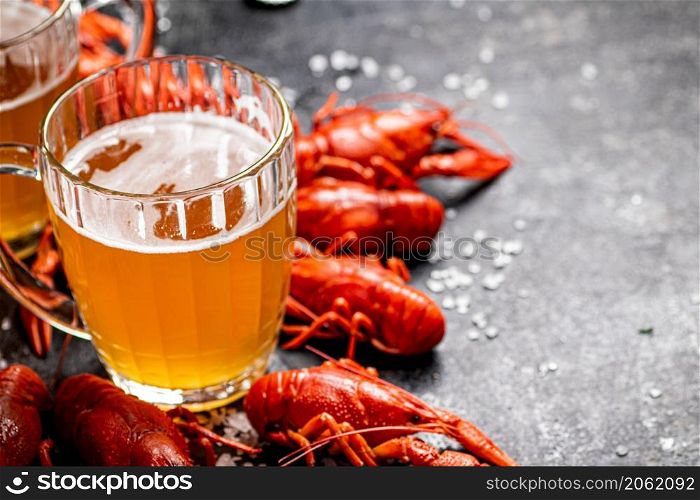 Boiled crayfish with a glass of beer. On a black background. High quality photo. Boiled crayfish with a glass of beer.