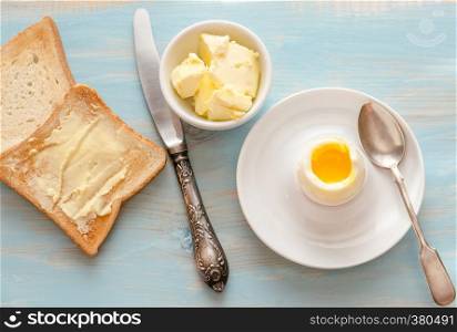 Boiled egg with crispy toasts on the wooden table