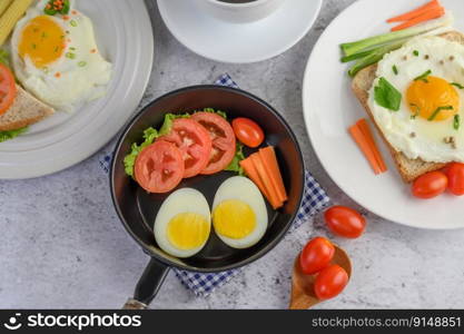 Boiled eggs, carrots, and tomatoes on a pan with tomato on a wooden spoon.