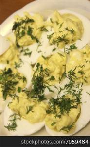 Boiled eggs sliced in halves stuffed and filling by pasta with dill