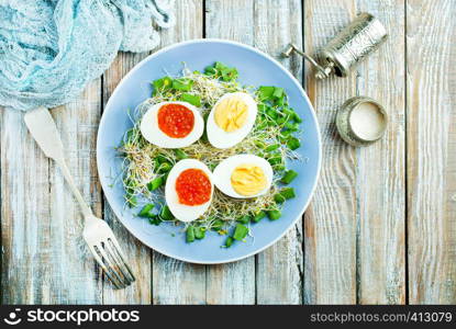 boiled eggs with red salmon caviar, salad on plate