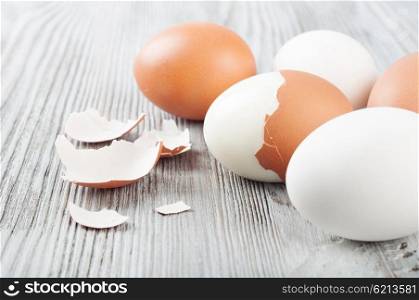 Boiled hen eggs and eggshell on a wooden background