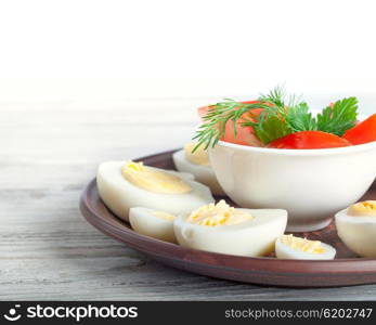 Boiled hen eggs in a clay dish on a wooden background
