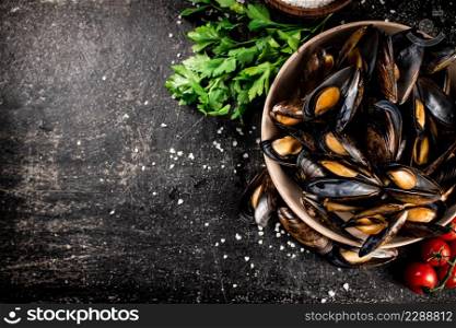 Boiled mussels in a bowl with parsley. On a black background. High quality photo. Boiled mussels in a bowl with parsley.