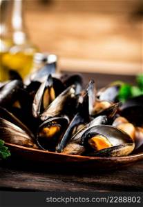 Boiled mussels in a plate with parsley. On a wooden background. High quality photo. Boiled mussels in a plate with parsley.