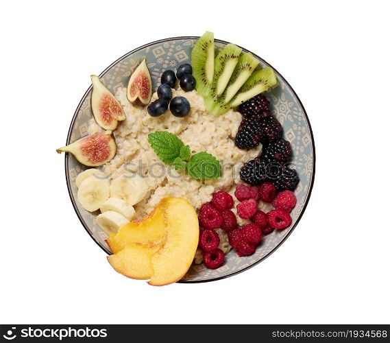 boiled oatmeal with fruits in a round plate on a white isolated background, top view. Morning breakfast