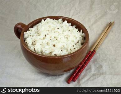Boiled oval rice with cumin in ceramic mug and chopsticks