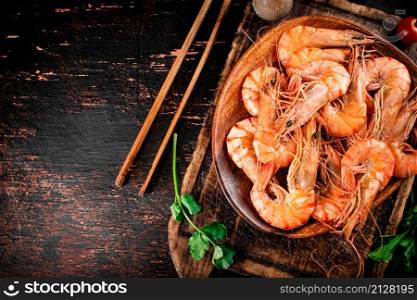 Boiled shrimp in a wooden plate. Against a dark background. High quality photo. Boiled shrimp in a wooden plate.