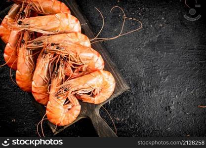 Boiled shrimp on a cutting board. On a black background. High quality photo. Boiled shrimp on a cutting board.