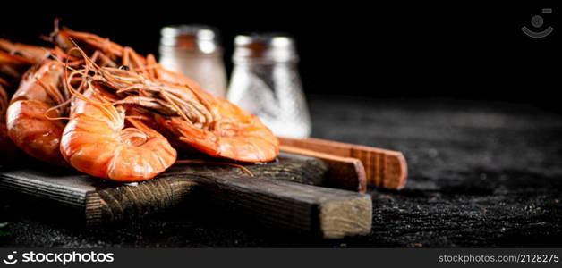 Boiled shrimp on a cutting board. On a black background. High quality photo. Boiled shrimp on a cutting board.