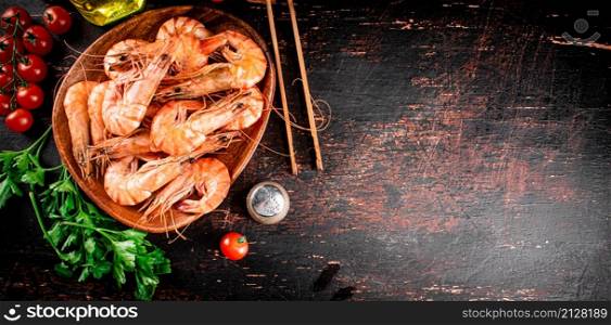 Boiled shrimp on a plate with tomatoes and parsley. Against a dark background. High quality photo. Boiled shrimp on a plate with tomatoes and parsley.