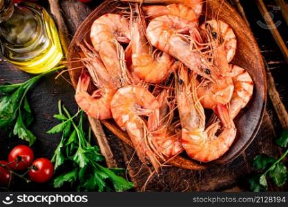 Boiled shrimp on a plate with tomatoes and parsley. Against a dark background. High quality photo. Boiled shrimp on a plate with tomatoes and parsley.