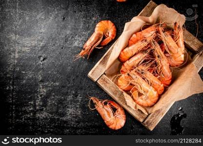 Boiled shrimp on a wooden tray. On a black background. High quality photo. Boiled shrimp on a wooden tray.