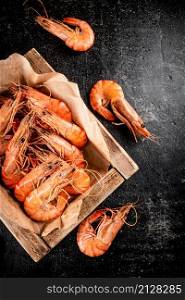 Boiled shrimp on a wooden tray. On a black background. High quality photo. Boiled shrimp on a wooden tray.