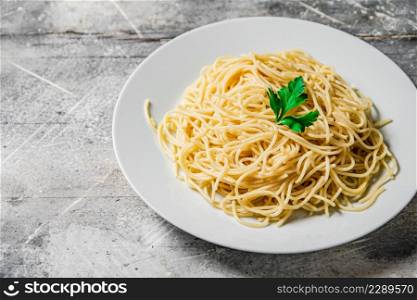 Boiled spaghetti in a plate with parsley. On a gray background. High quality photo. Boiled spaghetti in a plate with parsley.