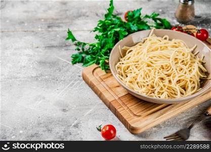 Boiled spaghetti in a plate with parsley. On a gray background. High quality photo. Boiled spaghetti in a plate with parsley.