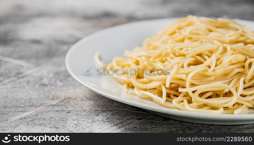 Boiled spaghetti on a plate. On a gray background. High quality photo. Boiled spaghetti on a plate.