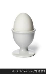 Boiled white egg in an eggcup on white background
