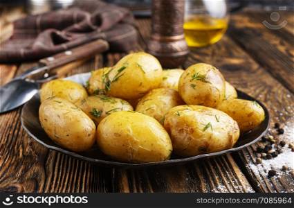 Boiled young potatoes with butter and dill on plate on a dark background.