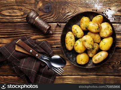 Boiled young potatoes with butter and dill on plate on a dark background.