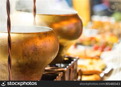 Boiling brass cauldrons or big pots on street food festival. Boiling brass cauldrons