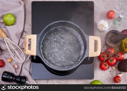 Boiling water in a cooking pot an a pan on a induction stove at domestic kitchen.. Boiling water in a cooking pot an a pan on a induction stove at domestic kitchen