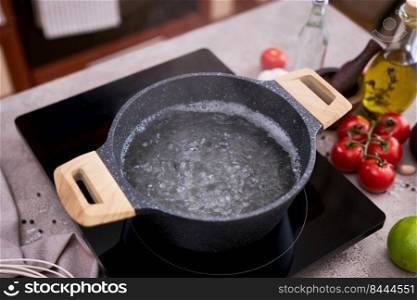 Boiling water in a cooking pot an a pan on a induction stove at domestic kitchen.. Boiling water in a cooking pot an a pan on a induction stove at domestic kitchen