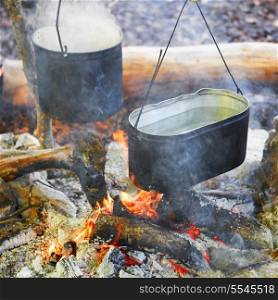 Boiling water in two pots above the fire.