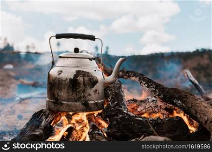 Boiling water on a camping trip with fire in the mountains, cooking on a fire with firewood. Kettle on fire. Picnic. Kettle on fire in the mountains wallpaper