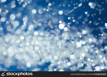 bokeh on blue background, water drops levitating and backlit by flash