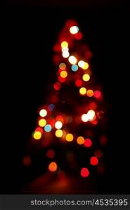 Bokeh silhouette of Christmas tree on black background