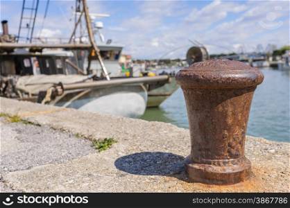 Bollard in the harbor, with the background of fishing boats