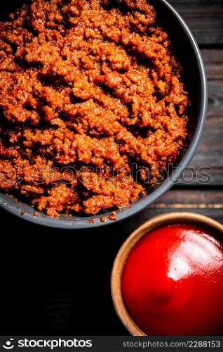 Bolognese sauce with tomato sauce in bowls. On a wooden background. High quality photo. Bolognese sauce with tomato sauce in bowls.