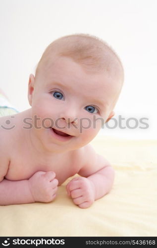 Bond little baby blue eyes lying down smiling on light yellow bed