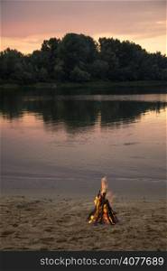 Bonfire on the bank of the river at sunset time
