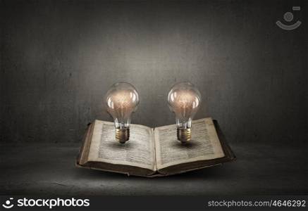 Book and light bulb. Glass glowing light bulb on opened book