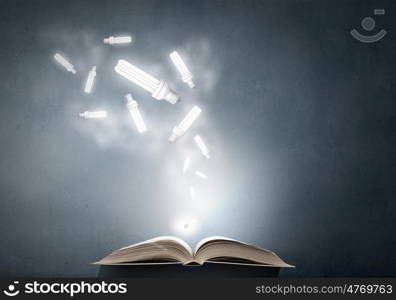 Book and light bulb. Opened book and glowing light bulbs flying from pages