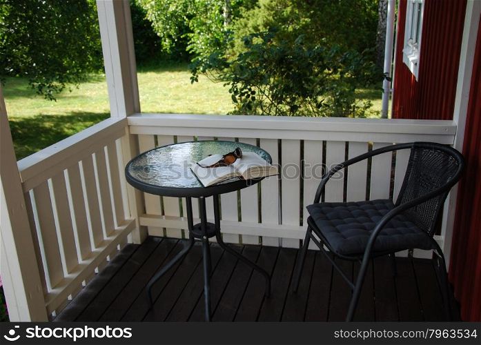 Book and sunglasses on a table at a porch in summer