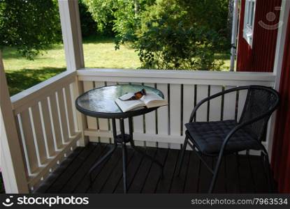 Book and sunglasses on a table at a porch in summer