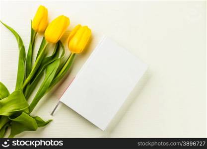book and yellow tulips on lighten background