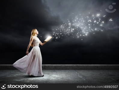 Book education. Young woman in white long dress with book in hand