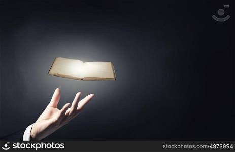 Book in hand. Close up of hand holding in palm glowing book
