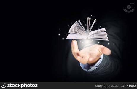 Book in hand. Close up of hand holding in palm glowing book